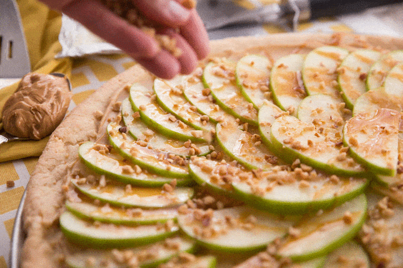 Taffy Apple Pizza // When you start with a sugar cookie crust, it's hard to go wrong. Add on a creamy layer of peanut butter and cream cheese. Top with sliced apples, caramel, and chopped nuts. This Taffy Apple Pizza will be the star of the party! | Tried and Tasty