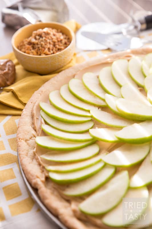 Taffy Apple Pizza // When you start with a sugar cookie crust, it's hard to go wrong. Add on a creamy layer of peanut butter and cream cheese. Top with sliced apples, caramel, and chopped nuts. This Taffy Apple Pizza will be the star of the party! | Tried and Tasty