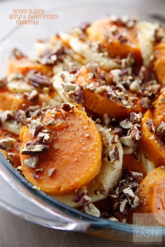 Close up of sliced baked sweet potatoes alternating with apple slices topped with chopped toasted pecans