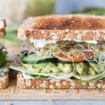 A close up photo of a Veggie Sandwich on a wooden cutting board