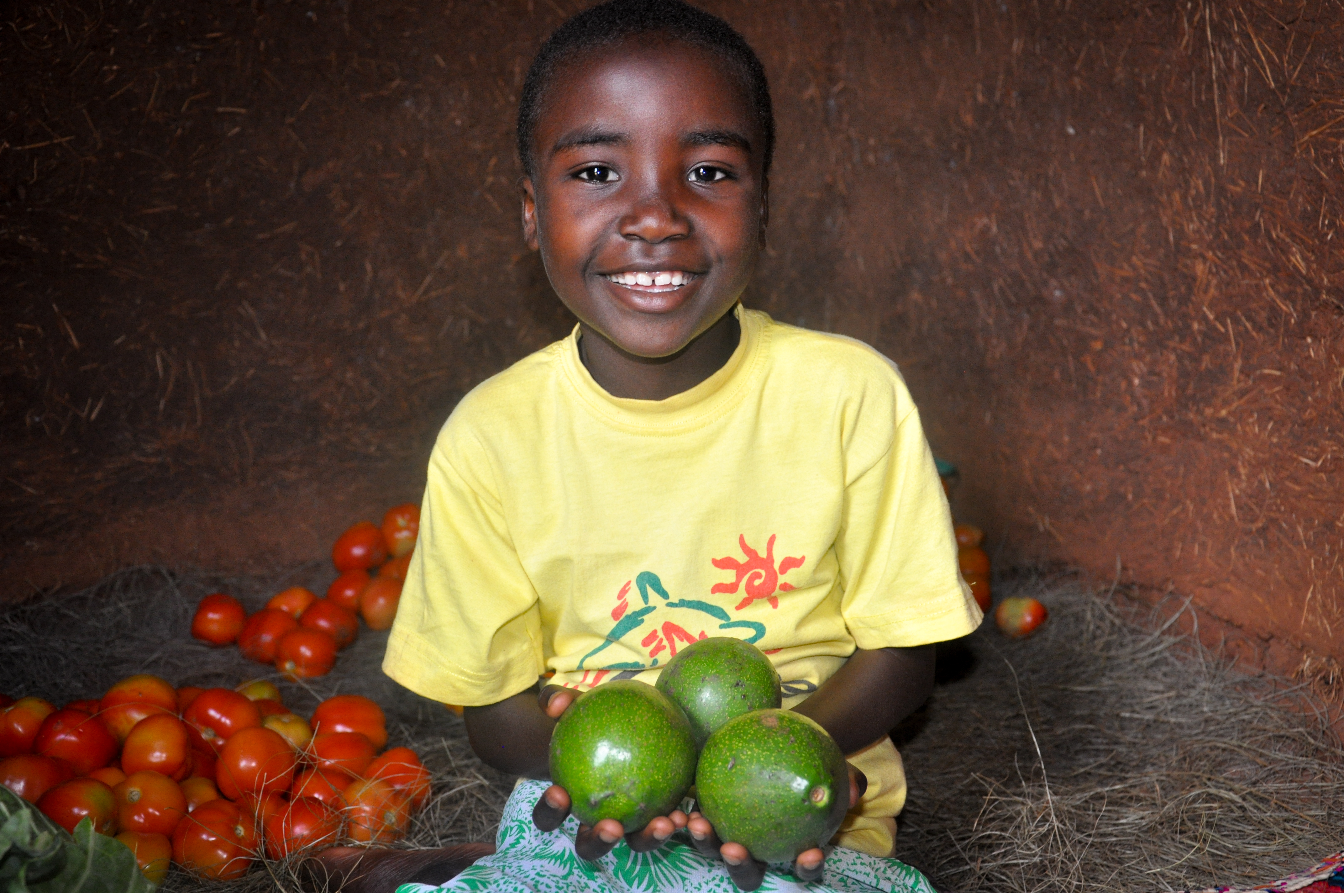 A World Vision Tanzania sponsored child Vanessa (6) happily holding avocadoes which shows food security at her home in Kitoko village located in north western Tanzania