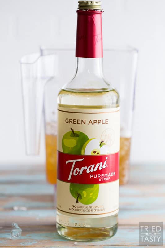 Torani Green Apple Puremade Syrup with Blender jar filled with Kombucha in the background.