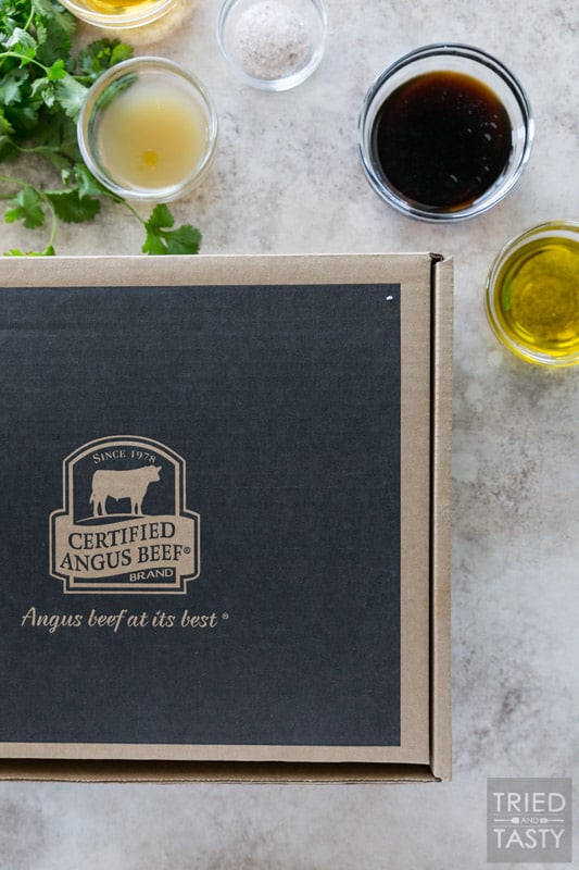 A cardboard box with the Certified Angus Beef ® brand logo on it. Marinade ingredients surround the box.