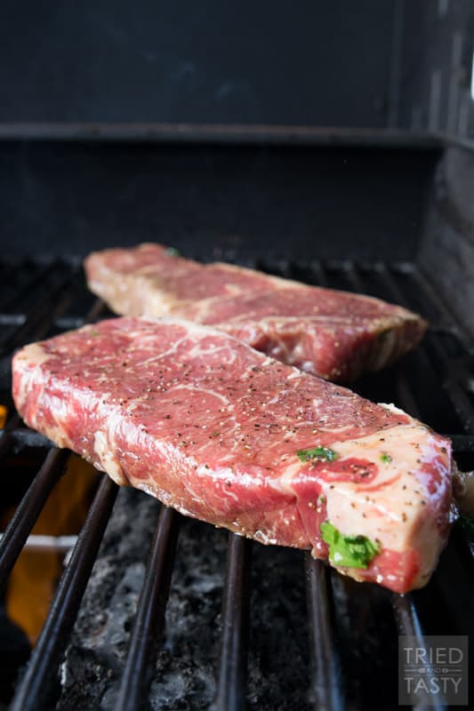 Strip steaks on a grill being cooked.