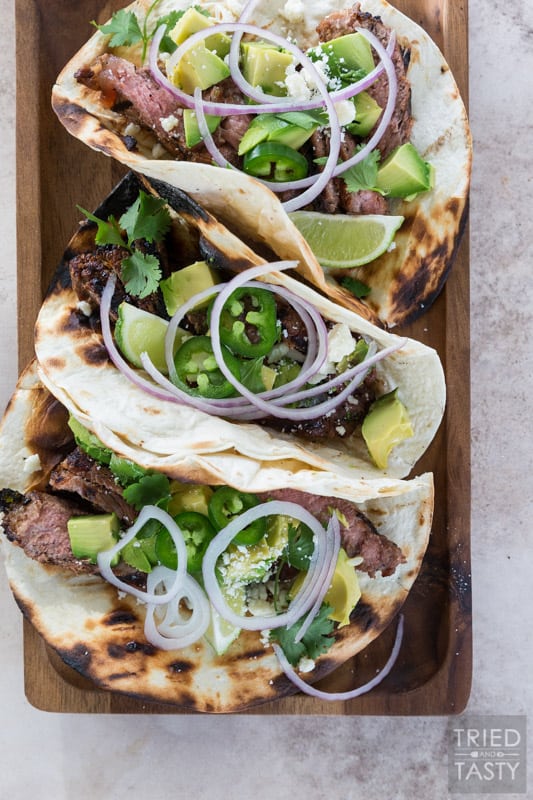 Assembled steak tacos placed on a cutting board.